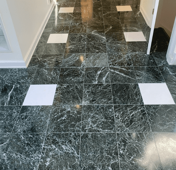 A marble floor with dark green tiles and white square tiles arranged in a repeating pattern, leading into a hallway.
